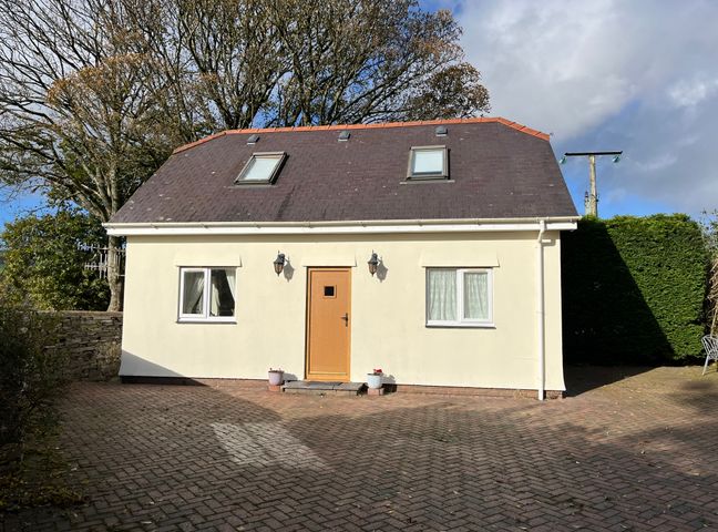 A small house with a brown door and two windows on the ground floor and two roof windows at Country View in Talysarn near Penygroes