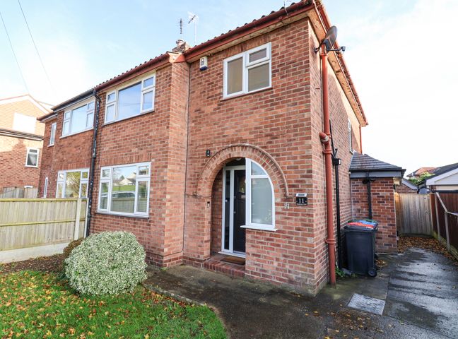 A brick semi detached house with white windows and a black front door at Rainbows End in Christleton