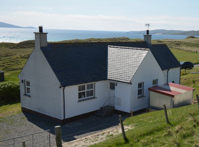 A white cottage with two chimneys and a gravel driveway near the coast at Taigh Marsaili in Luskentyre Isle Of Harris