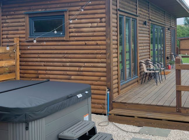 An outdoor area with a hot tub and chairs at Primrose in Higher Wambrook near Chard