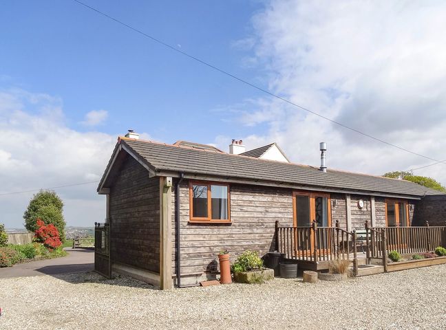 A wooden house with a gravel driveway and small garden at Lilys Pad in Okehampton