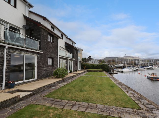 A row of houses with balconies beside a lawn and boats in a marina at 9 Oakley Wharf in Porthmadog