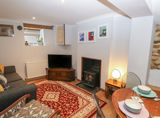 A living room with a patterned carpet a sofa a TV near a fireplace and a set dining table at 5A Castle Street in Ryde