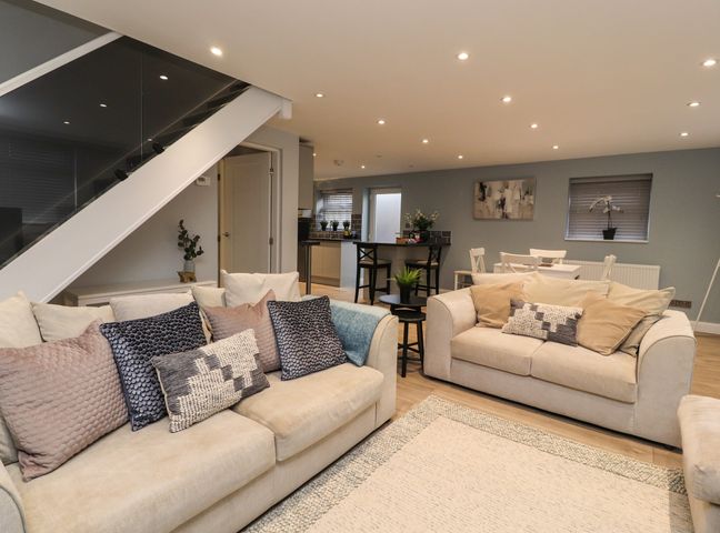A living room with two sofas and a small table next to a staircase at The bungalow at 46 Church St in Adlington