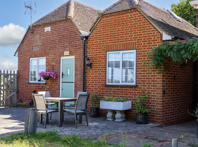 A brick house with a green door and outdoor table with four chairs at The View in Goodnestone near Faversham