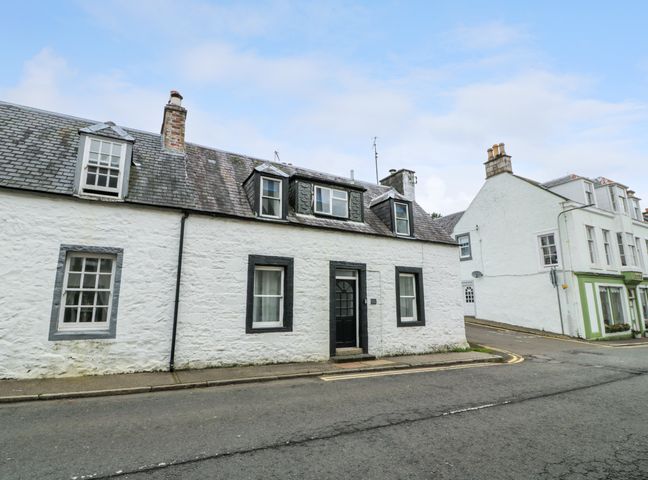 A street view of white stone cottages with slate roofs and chimneys in Corner Cottage New Galloway