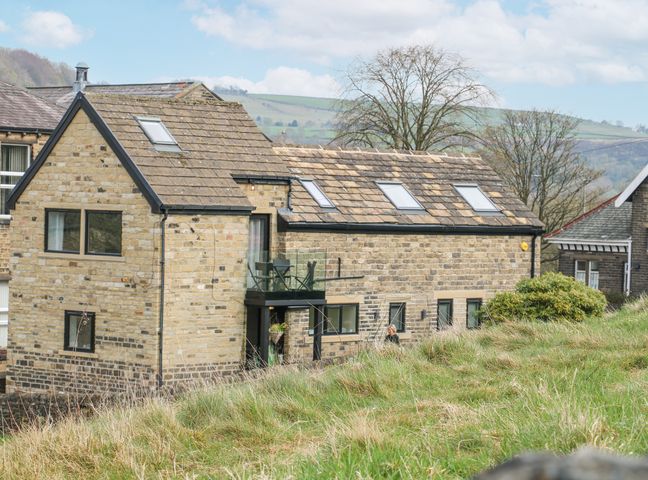 Stone house with multiple skylights and a glass balcony surrounded by grass at The Old Telephone Exchange in Marsden