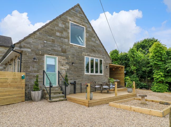 Stone house exterior with a wooden deck patio furnished with chairs and table at Cherry Tree Cottage in Chesterfield