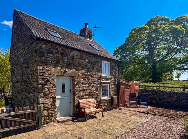 A stone house with a bench and chairs at School House Cottage Newtown near Longnor