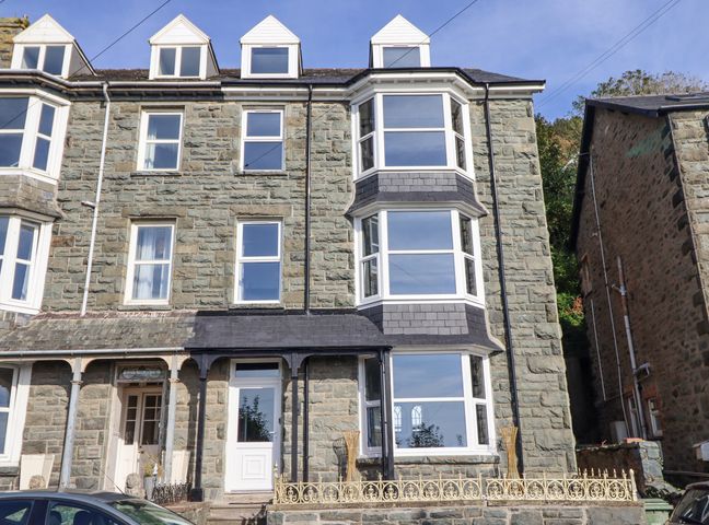 Stone townhouse with bay windows and a black roof in Barmouth