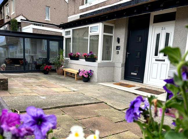 The front entrance of a house with two doors a bench and several flower pots outside Brynmar in Heysham