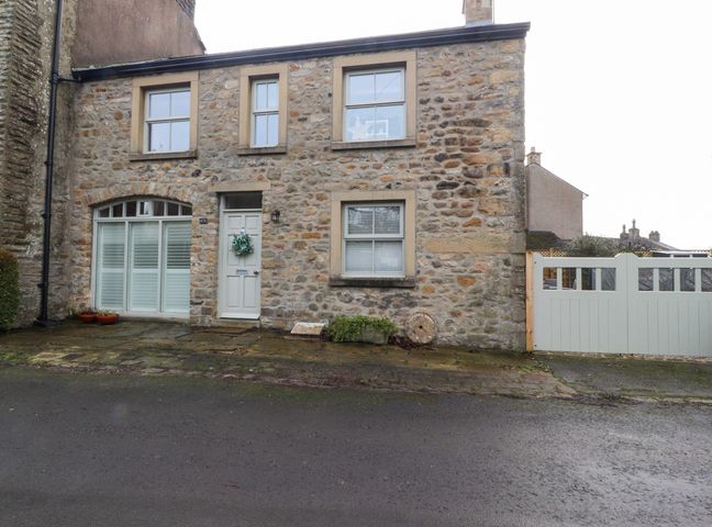 A stone house with windows a door and a white gate at Chapel Croft in Long Preston