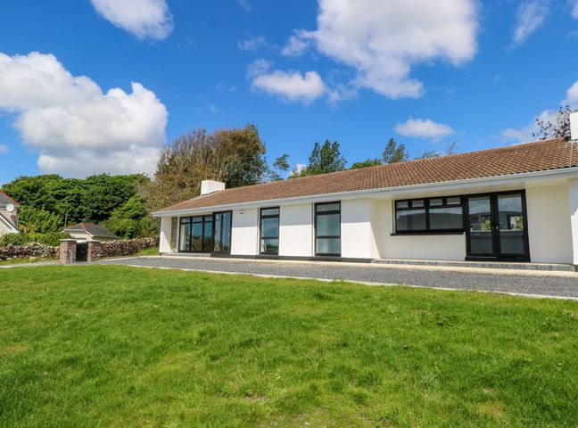 A single story house with multiple windows and a tiled roof with a green lawn in front at Cushranny in Mulranny County Mayo