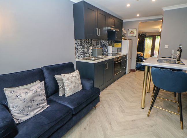 A kitchen with dark cabinets a blue sofa and a dining table with blue chairs at Foxgloves in Castleton Peak District