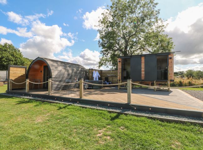 A wooden pod and a small wooden building with doors on a deck with rope fencing at Hawkstone Kenstone near Hodnet