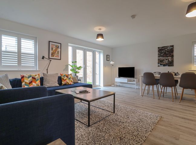 A living room with sofas coffee table TV and dining table with chairs at Inishnee House in Shotley Gate