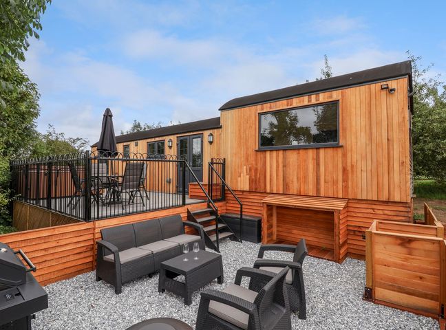An outdoor patio area with black metal furniture and a wooden building at The View in Bangor-On-Dee