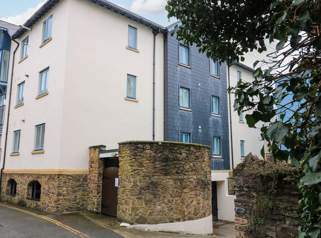 An exterior view of a multi-story building with stone walls and blue window frames at 8 Dartmouth House in Dartmouth