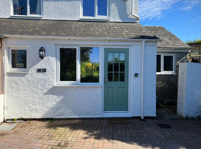 An exterior view of a house with a blue door and windows at Elder Cottage Studio Perranwell Station near Ponsanooth