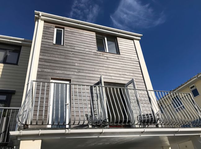 Exterior view of a two-story house with wooden paneling a balcony and metal railing at 6 Inveravon in Christchurch