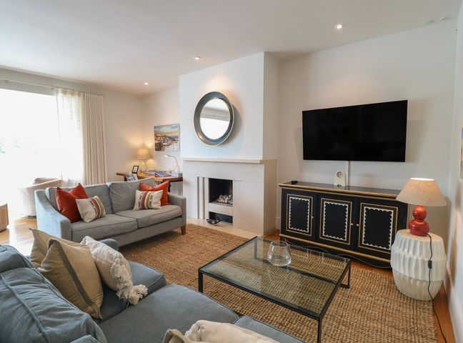 A living room with a sofa, armchair, coffee table, and television at 22 Dart Marina in Dartmouth