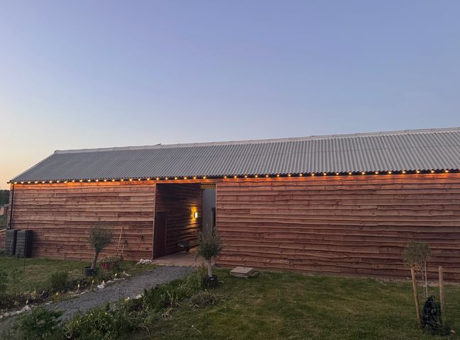 An exterior view of a wooden building with lights at Number 3 The Barn House in Woodham