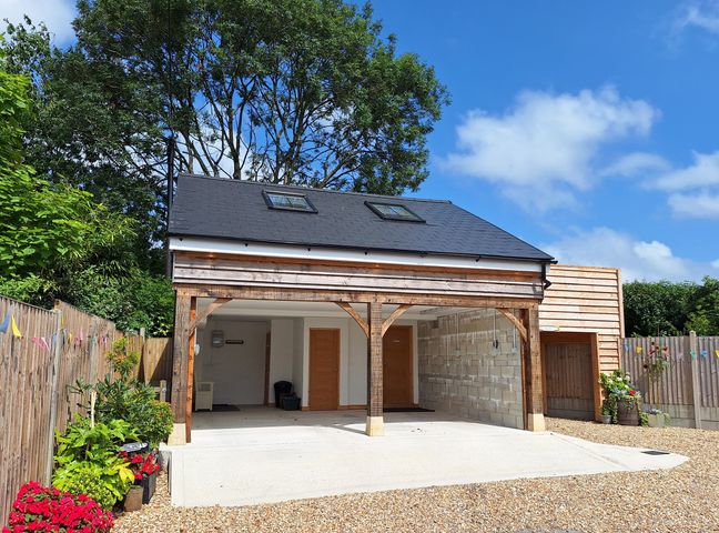 A carport with gravel driveway and trees at The Halt in Maiden Newton