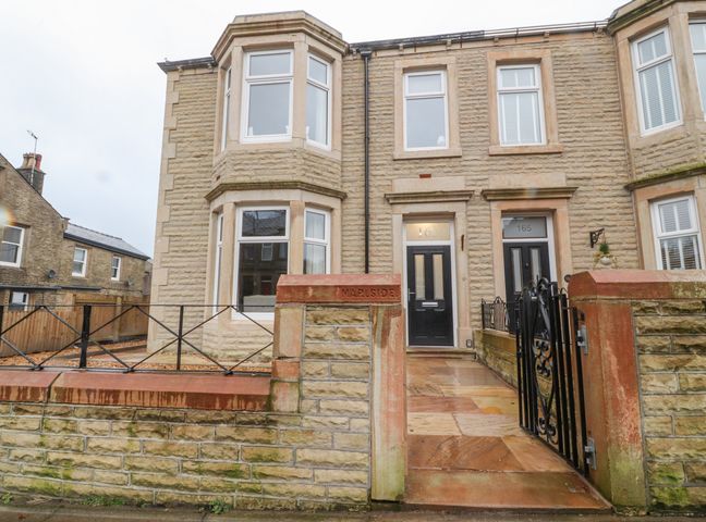 The front exterior of a stone house with black front doors and low stone walls at 163 Manchester Road in Accrington