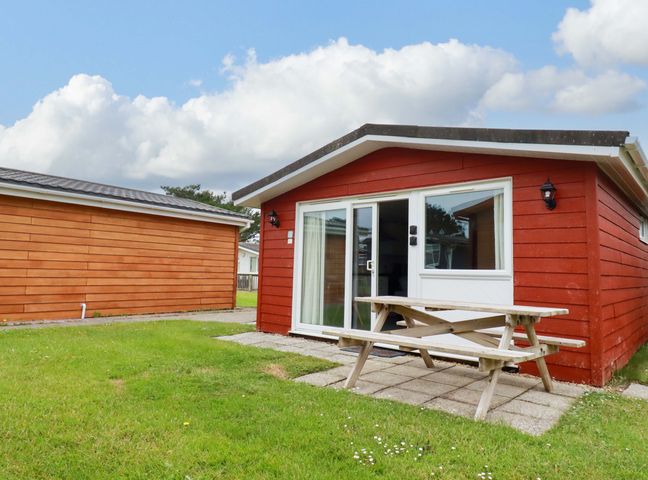 A cabin with a picnic table and grass at H2 Atlantic Bay Holiday Park in Padstow