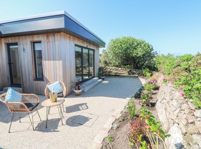 A garden patio with two chairs and a small table outside a wooden house at Little Victory in Pendeen