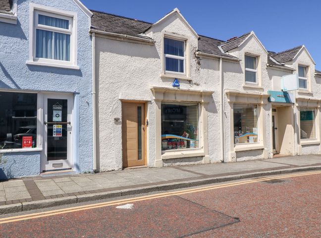 A street view of small commercial buildings with display windows and doors at Medical Hall in Cemaes Bay