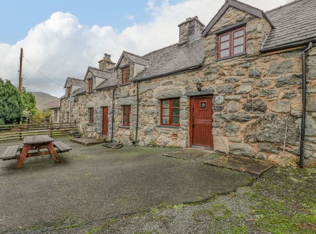 Stone cottages with brown wooden doors and windows and a picnic table outside at Ysgubor in Dinas Mawddwy near Dolgellau