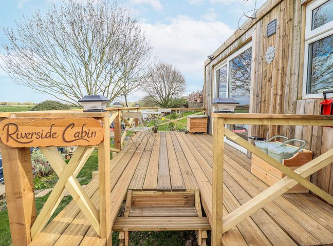 An outdoor deck with a sign at Riverside Cabin in Peterborough