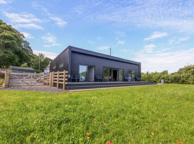 An outdoor view of a house with patio and fence at Y Cwt Moelfre
