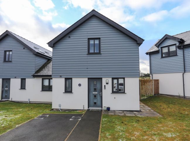 Front view of a modern detached house with a driveway and grass lawn at 19 Parc Delfryn in Benllech