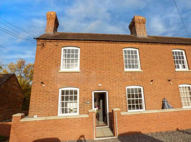 A brick house with two chimneys and four windows with white frames at 1 Willow Cottage in Upton Upon Severn