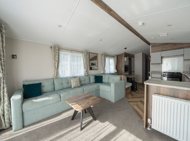 A living room with a large sectional sofa and coffee table next to an open kitchen and dining area at Stillwater Retreat  Billing Aquadrome Holiday Park