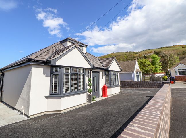 A bungalow with bay windows and a brick wall in front at Ty Blodau near Prestatyn