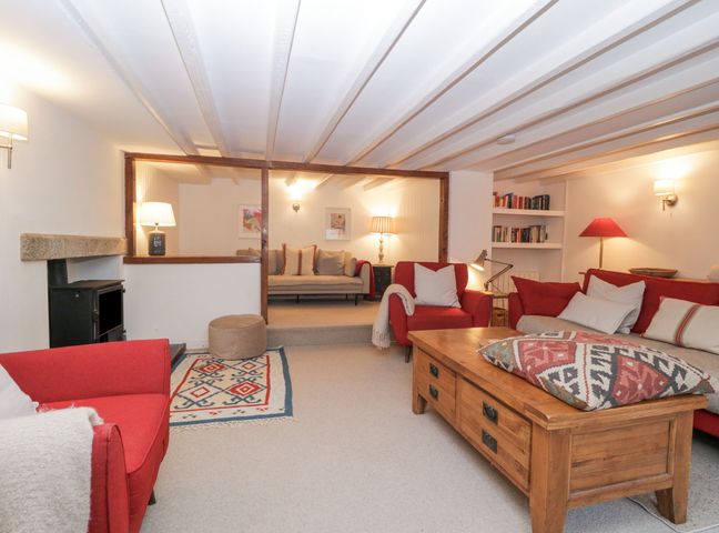A living room with red chairs wooden coffee table and a small sitting area at Springfield in Kingsand