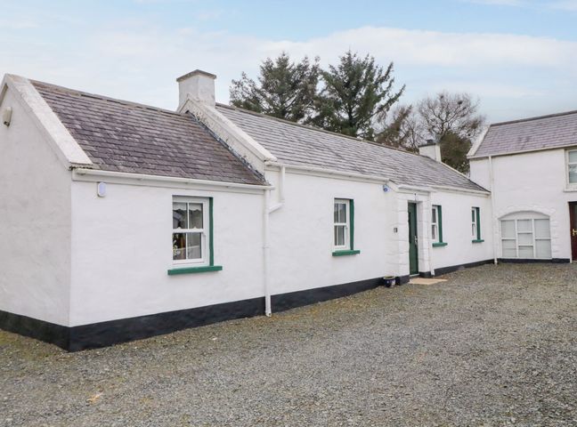 A white cottage with green window frames and a green door surrounded by gravel at Ballard Cottage Lislea near Newry
