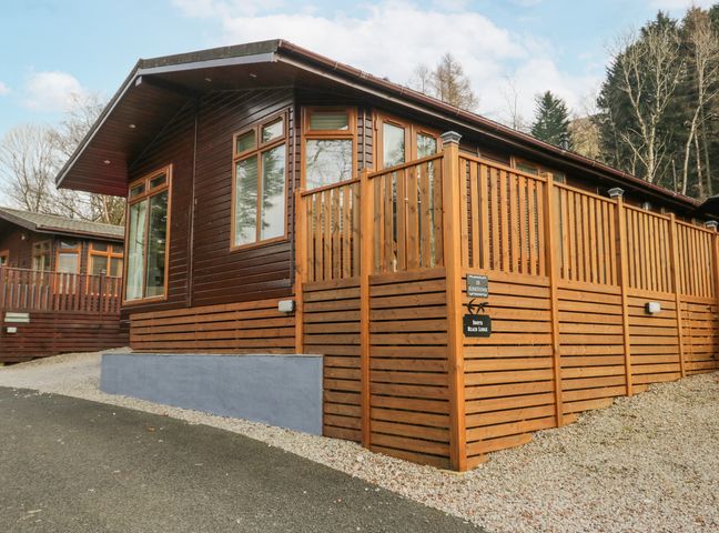 A wooden lodge with large windows and a fenced deck at Swifts Reach Lodge Kirkstone 10 Limefitt Park near Windermere