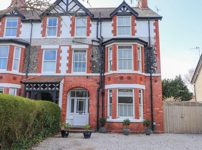A red brick and white window house with potted plants and an arched doorway at Dolawen Bach in Conwy