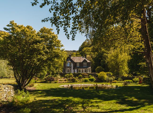 A house surrounded by trees and a pond in the garden at Leathes Head Country House Borrowdale near Keswick