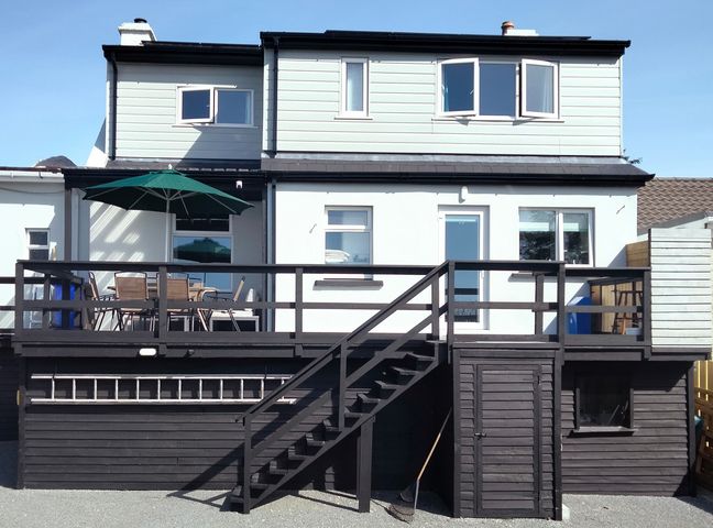 The back of a two story house with a raised deck patio and outdoor furniture at Gweedore Homestead in Bunbeg near Derrybeg County Donegal