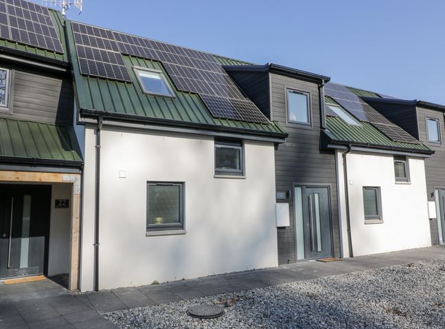 Exterior view of modern townhouses with solar panels on green metal roofs at Tay View in Aberfeldy