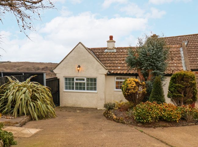 Exterior view of a house with tiled roof and garden shrubs at Meadow Cottage in Staintondale near Cloughton