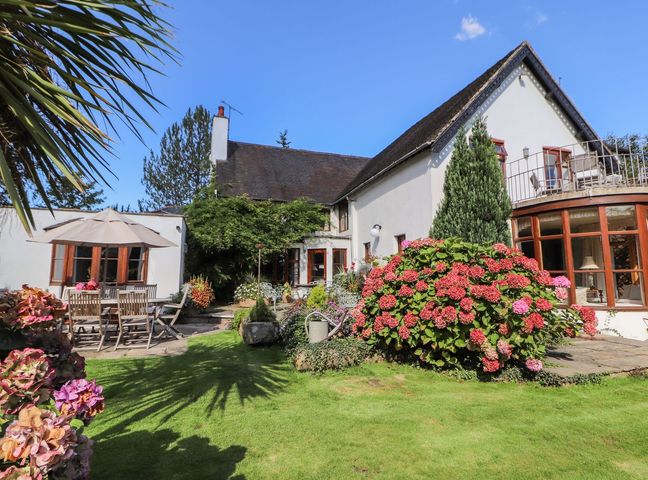 A garden with patio furniture and flowering bushes outside a white house at Mickle Trafford Manor in Chester