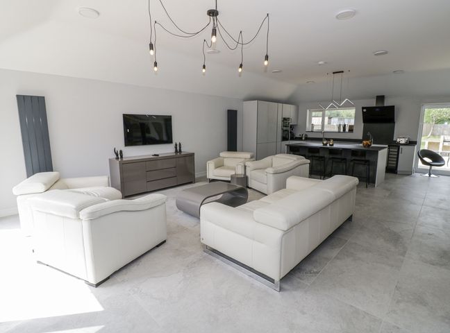 A living room with a television and kitchen island at Chillon South Littleton near Honeybourne