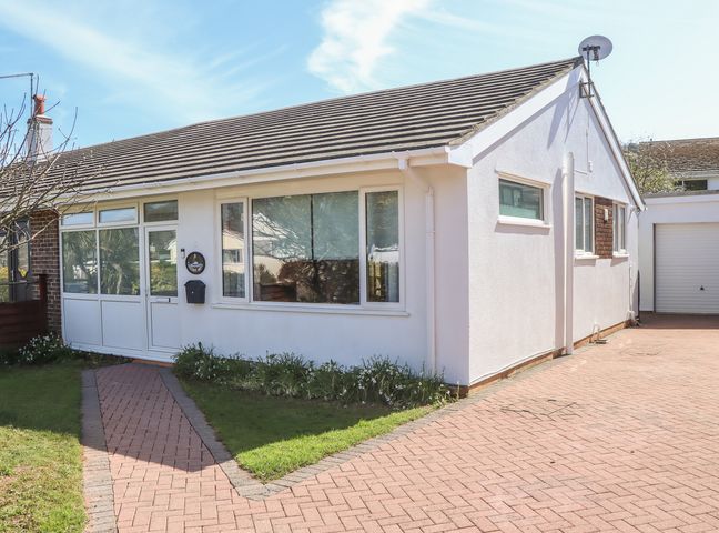 A single-story house with white walls a paved driveway and front entrance at 8 Chestnut Drive in Brixham
