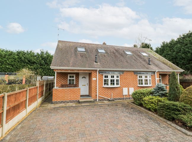 A brick semi detached house with skylights and a paved driveway surrounded by fencing and shrubbery at Rooster in Stourport-On-Severn